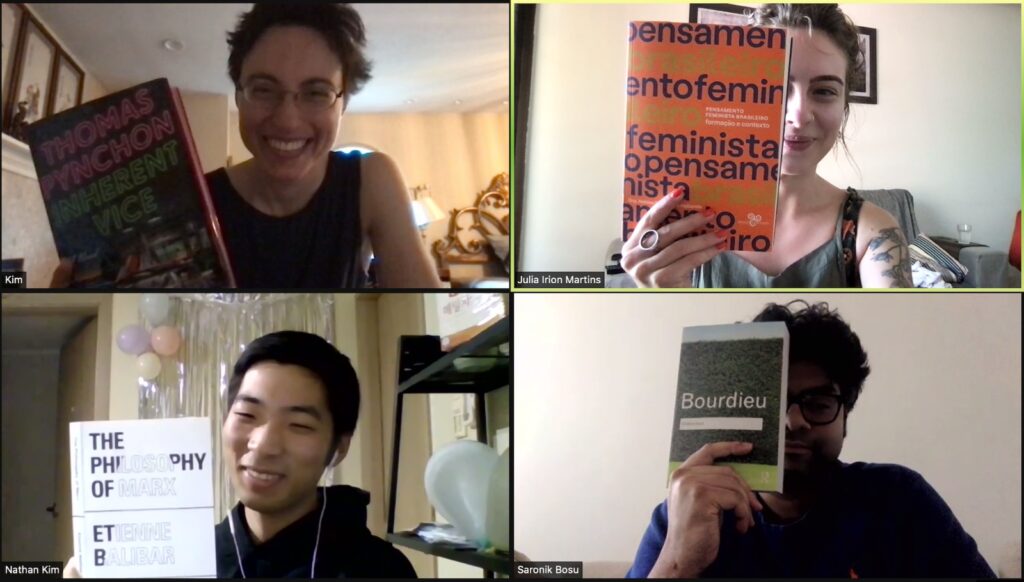 Screenshot from a Zoom meeting showing four people holding up books.