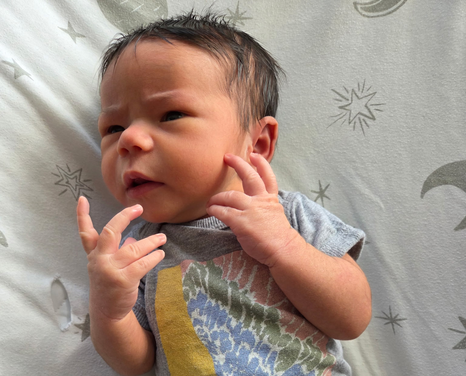 Photograph of a human infant, making a very philosophical gesture, wearing a high theory onesie.